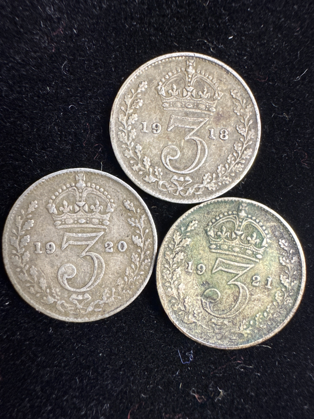 Three circulated British silver threepence coins dated 1918, 1920, and 1921
